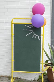 Outdoor chalkboard as an advertising panel with balloons and a painted sun symbol