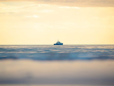 One small fishing boat heading out on the foggy ocean at dawn. Boat on the background of sunset. The Baltic Sea close up, stormy dramatic dark clouds. The Vacation, summer concept