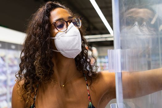 Brazilian young woman shopping in the supermarket with mask. New normality concept.