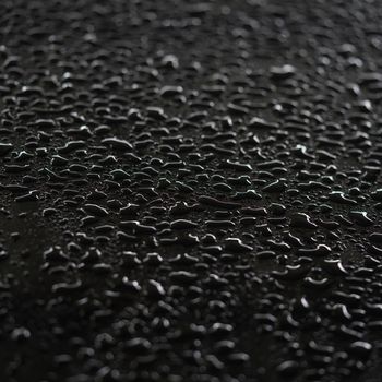 Abstract raindrops clinging to the surface of the car, black background.