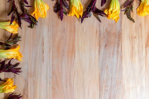 Wooden background with pumpkin flowers and purple epazote, for copy space. Food background