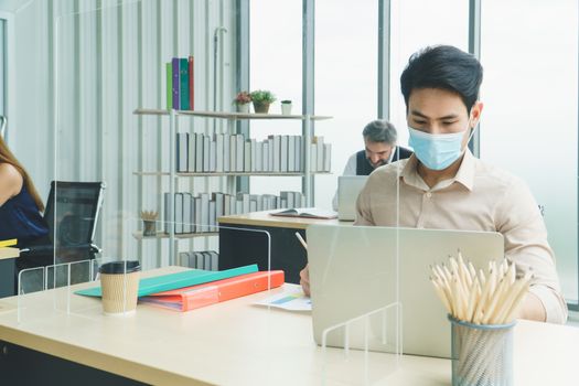 Business people wear a protective mask to work together in the company office. social distancing is the new normal. The concept of preventing the spread of coronavirus or COVID-19