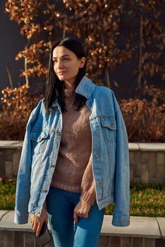 Calm and positive young female standing in a relaxed pose in the cosy alley of a quiet city square