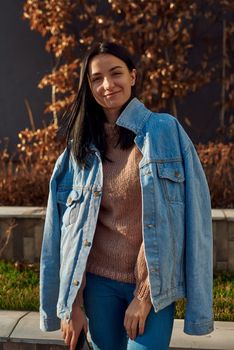 Cropped portrait of a cheerful young female brunette in casual clothes posing outdoors on autumn background