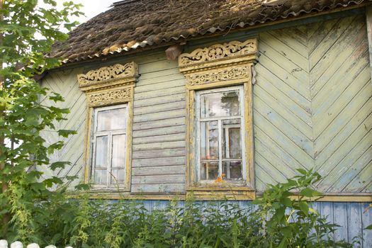 Old wooden shabby house in village in Belarus. Windows and bushes