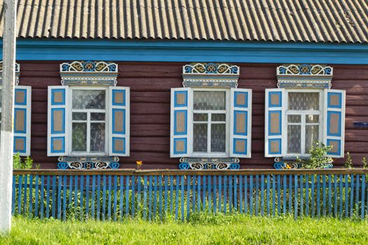 Vintage colorful wooden ornamental carved windows, frames on facade of rustic folk house. Belarus