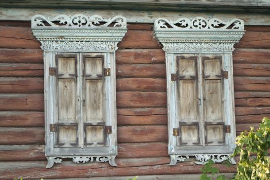 Carved wooden window with shutters. Old wooden window shutters on a log wall. Traditional wood carving, Belarus. Close up