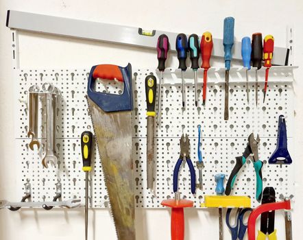 Front view of the white tool board with various hanged tools.