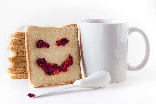 A smile at breakfast, made of strawberry jam, spread on a slice of bread.