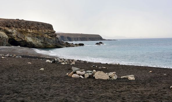 Beach with black sand near rocky coast in Ajuy village, Fuerteventura, Spain.