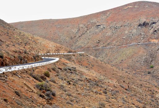 View of beautiful mountain scenery with road with white bollards in Fuerteventura island.