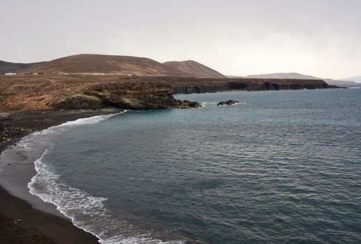 Beach with black sand near rocky coast in Ajuy village, Fuerteventura, Spain.