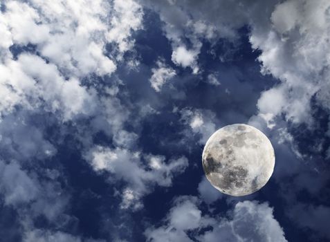 Full moon in midnight deep blue sky with clouds.