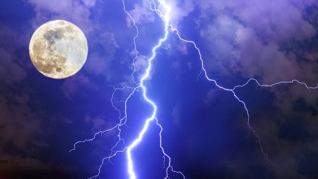 Dramatic thunderstorm night sky with big lightnings, clouds and full moon.