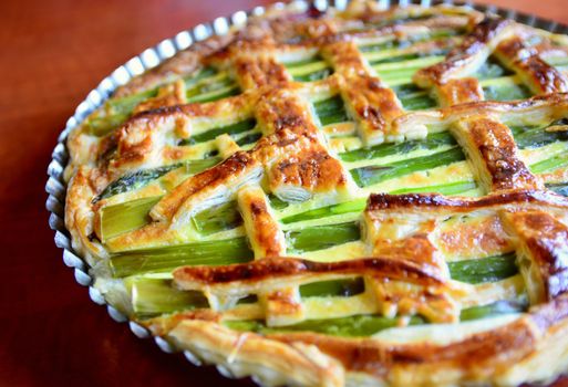 Top view of an Asparagus cake with puff pastry, cheese, ham and spinach in the one pan.