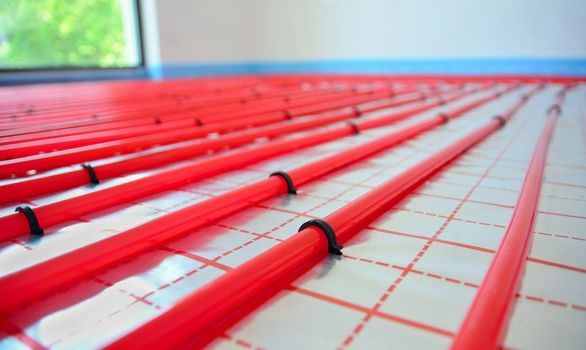 Water underfloor heating pipes on the silver reflective foil in house construction.