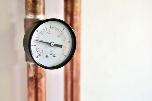 Closeup of pressure gauge connected to copper heating pipe.