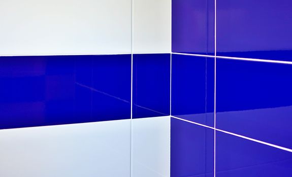 Blue and white gloss tiles with white joints in bathroom corner.