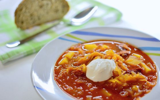 Traditional red cabbage soup with red pepper spice and sour cream on top.