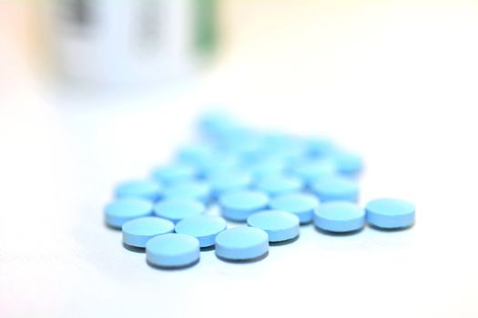 Closeup of a Blue Drug Pills Spilling Out of a Bottle on the White Background.