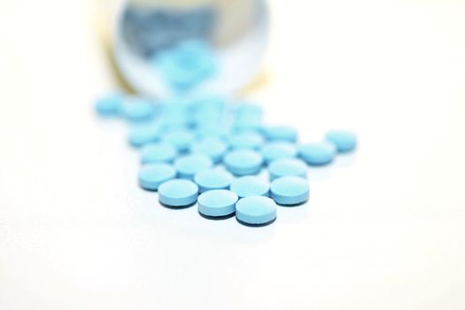 Closeup of a Blue Drug Pills Spilling Out of a Bottle on the White Background.