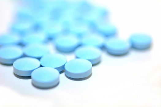 Macro of a Blue Pills on the White Background.