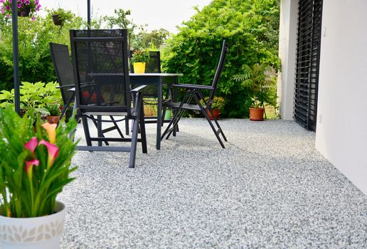 Beautiful Terrace with Decorative Natural Stone Floor, Potted Flower and Table with Chairs.