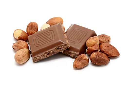 Two squares of hazelnut milk chocolate bar with whole hazelnuts over white background.