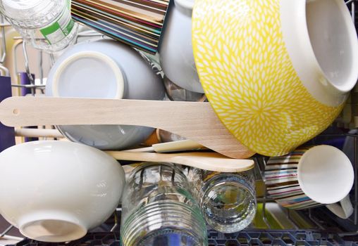 Top view of cleaned different dishes in dishwasher rack.