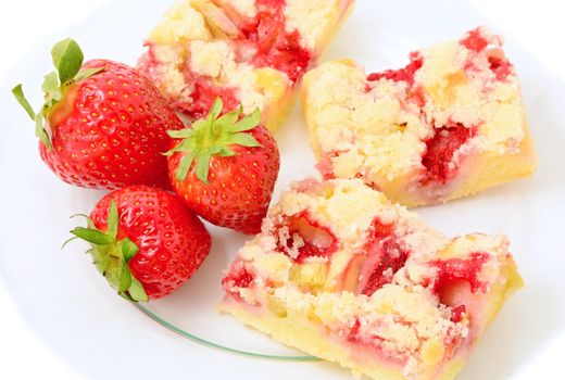 Sliced strawberry cakes with whole fresh strawberries on glass plate over white background.