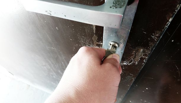 Close-up of hand with key unlocking the metallic door.