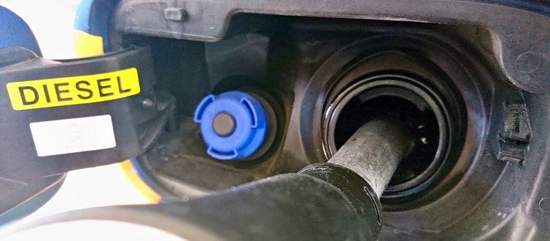 A closeup of a refueling gun put into a car during diesel refueling.