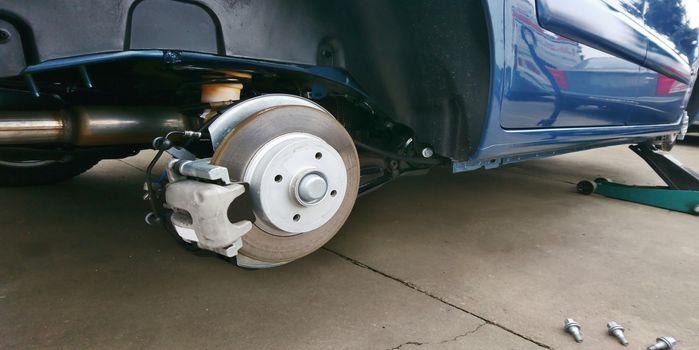 Close-up of a car disc brake with caliper during tyre replacement. Car maintenance.