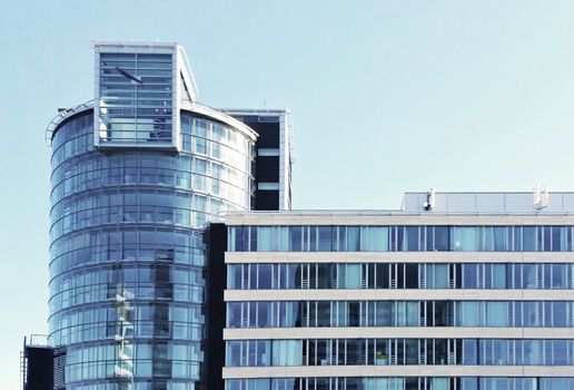 A front view of modern office glass building exterior against the blue sky.