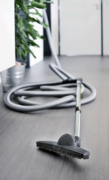 Central vacuum cleaner hose laid on the floor in the living room. Cleaning room conceptual shot, focused on foreground.