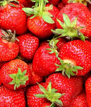 Full frame background with juicy fresh whole strawberries with green leaves.