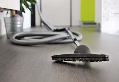 Central vacuum cleaner hose laid on the floor in the living room. Cleaning room conceptual shot, focused on foreground.