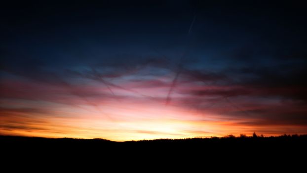 Beautiful pre-down vivid deep blue orange sky during sunrise over silhouetted horizon.