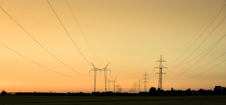 Large transmission towers at sunset with horizon