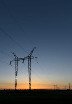 Large transmission towers at sunset with horizon