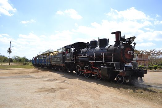 Trinidad, Cuba, February 2011: old steam train rom Trinidad to the Sugar Mills' Valley - Valle de los Ingenios in Cuba pulling in the city, crossing a dirt road.