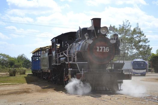 Trinidad, Cuba, February 2011: old steam train rom Trinidad to the Sugar Mills' Valley - Valle de los Ingenios in Cuba pulling in the city, crossing a dirt road.