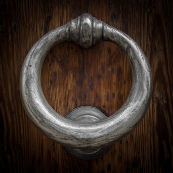Old brass knocker on wooden door.