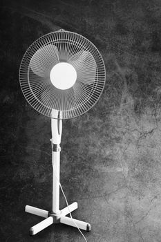 Convenient powerful fan for cooling the air in the apartment or office in hot weather. Presented on a dark background in the grunge style. Front view, copy space.