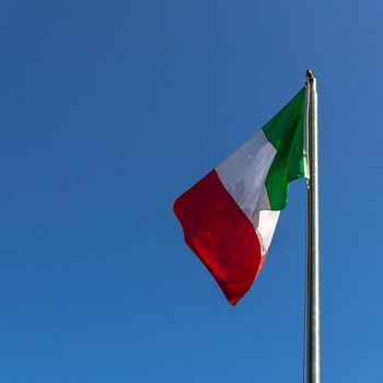Italian flag with clear blue sky in the background.