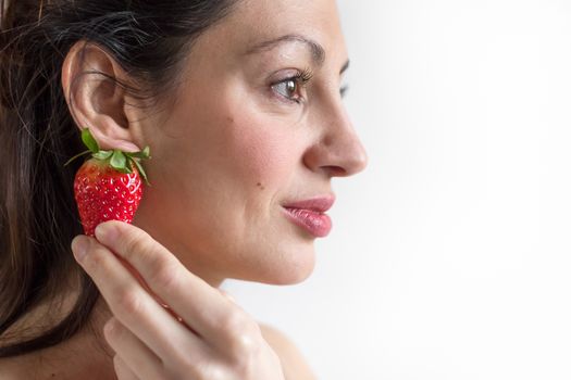 A beautiful woman wearing a strawberry as earring.