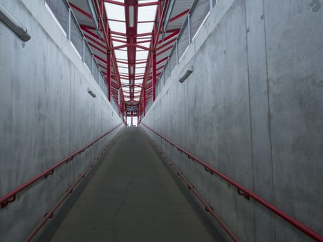 Empty concrete undergound passage platform subway on train station, gray and red, diminishing perspective.