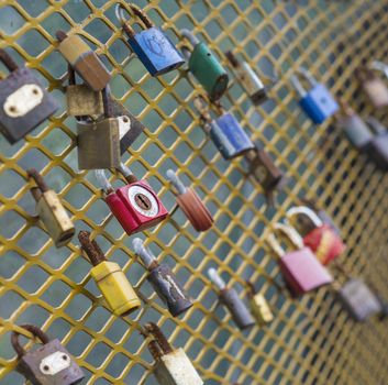 colorful locks hanging from yellow chain fence