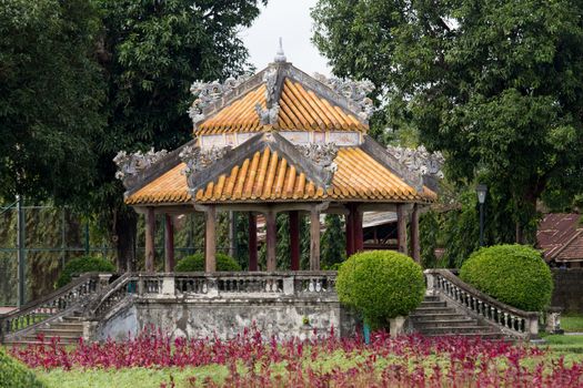 Hue, old capital of Vietnam from 1802 to 1945. Temple with yellow enamelled roof tiles in the lush gardens. Architecture and details of buildings. A major attraction is its vast, 19th-century Dai Noi Citadel, surrounded by a moat and thick stone walls. It encompasses the Imperial City, with palaces and shrines. High quality photo