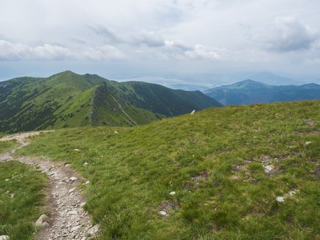 View from Banikov peak on Western Tatra mountains or Rohace panorama. Sharp green mountains - ostry rohac, placlive and volovec with hiking trail on ridge. Summer blue sky white clouds